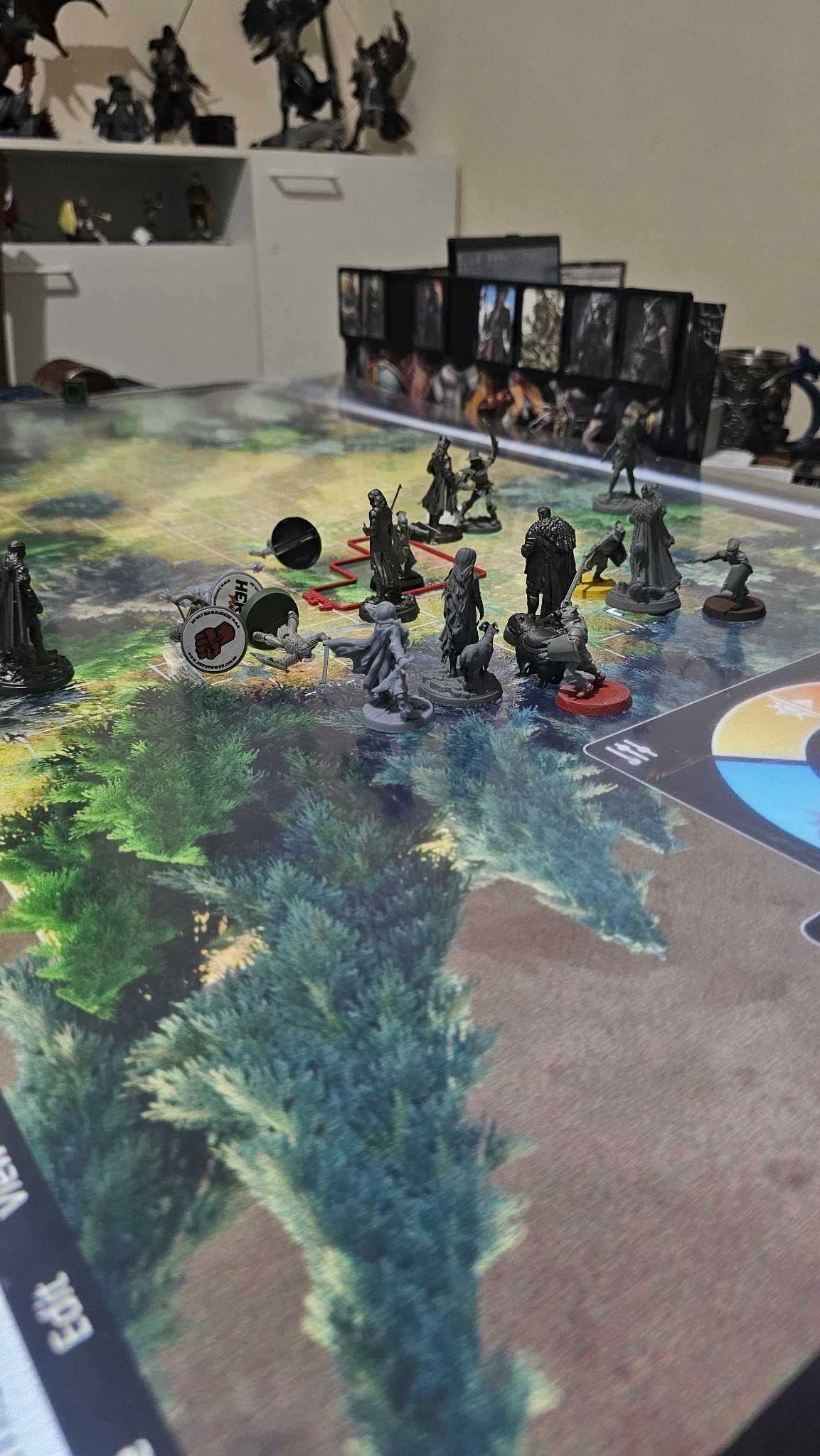 Miniaturas de personagens em um mapa de floresta, diante do escudo do narrador